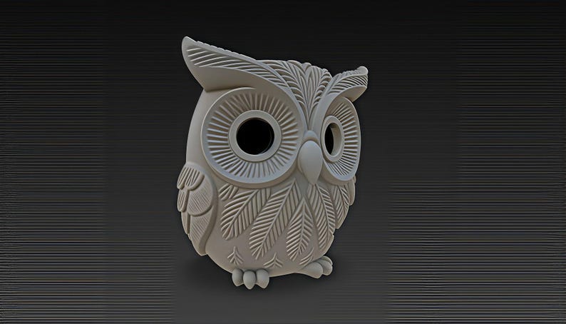 May include: A light gray owl figurine with detailed feather and eye designs. The owl has large, round eyes and a textured surface. The figurine is set against a dark gray background with horizontal lines.