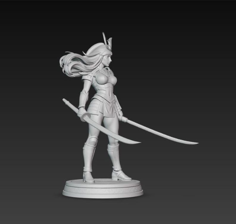May include: A detailed, monochromatic figurine of a female warrior, clad in armor and holding two curved swords. The figure has long flowing hair and stands on a circular base. The overall design suggests a fantasy or historical theme.
