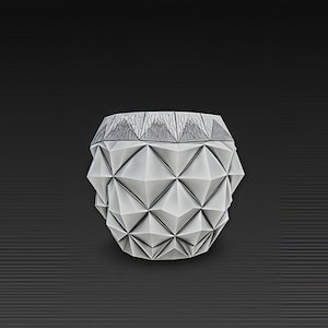 Op de afbeelding: Een geometrische, wit en grijze decoratieve container met een textuur, origami-achtig ontwerp. De container heeft een facet oppervlak en een contrasterende grijze rand. De achtergrond is donkergrijs met horizontale lijnen.