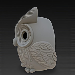 May include: A light gray owl figurine with detailed feather and eye designs. The owl has a large head with a prominent beak and large, round eyes. The figurine is a decorative item.