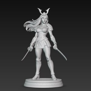 May include: A detailed, monochromatic sculpture of a female warrior in a dynamic pose. She is clad in stylized armor, holding two swords. Her long hair flows, and she wears a horned helmet. The figure stands on a circular base, showcasing intricate details.