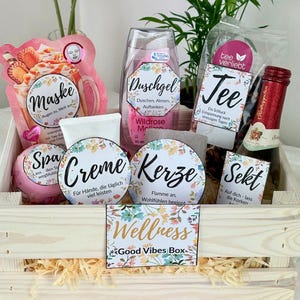 Könnte beinhalten: Eine Holzkiste gefüllt mit Wellnessprodukten, darunter eine Gesichtsmaske, Duschgel, Tee und eine Flasche Sekt. Die Kiste enthält auch eine Badekugel, Creme, Kerzen und ein Schild mit der Aufschrift "Wellness Good Vibes Box".