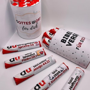May include: A set of small chocolate bars wrapped in red and white foil with inspirational Bible verses printed on the wrappers. The bars are arranged in two white cardboard tubes with black text that reads "Gottes Wort f&uuml;r dich" and "Bibel Verse f&uuml;r dich".