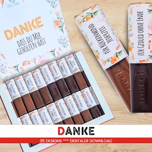 Op de afbeelding: Een doos Merci-chocolade met verschillende Duitse zinnen op de verpakkingen, waaronder "Danke" (Dank u). De doos is versierd met bloemmotieven en bevat individuele chocoladerepen. De afbeelding toont ook twee individuele chocoladerepen.