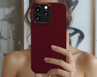 Puede incluir: Una funda de teléfono de color burdeos con una protuberancia de cámara elevada y tres lentes.