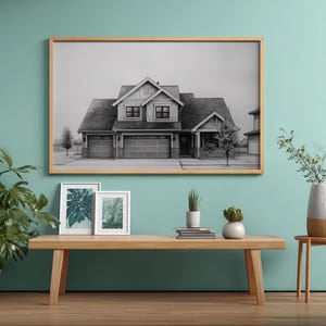 Może przedstawiać: Oprawiony czarno-biały wydruk domu wisi nad drewnianą ławką. Na ławce znajdują się dwa mniejsze oprawione wydruki botaniczne i rośliny doniczkowe. Duża roślina doniczkowa i wazon z gałęziami r&oacute;wnież znajdują się w pokoju. Ściana jest pomalowana na jasny turkusowy kolor.