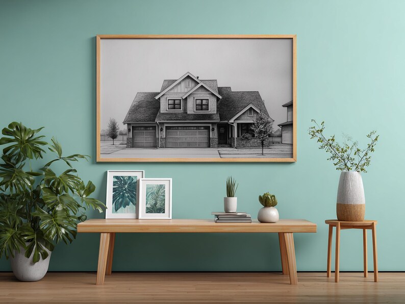 Może przedstawiać: Oprawiony czarno-biały wydruk domu wisi nad drewnianą ławką. Na ławce znajdują się dwa mniejsze oprawione wydruki botaniczne i rośliny doniczkowe. Duża roślina doniczkowa i wazon z gałęziami r&oacute;wnież znajdują się w pokoju. Ściana jest pomalowana na jasny turkusowy kolor.