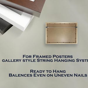 Może przedstawiać: Prostokątna rama obrazu z systemem zawieszania na sznurku w stylu galerii. Rama jest gotowa do zawieszenia i r&oacute;wnoważy się nawet na nier&oacute;wnych gwoździach. Na zdjęciu widać r&oacute;wnież stos czarnych, białych i brązowych ram.