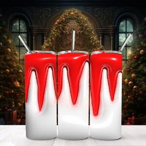 May include: Three white stainless steel tumblers with red dripping paint design. The tumblers are on a wooden surface with a Christmas tree and fireplace in the background.