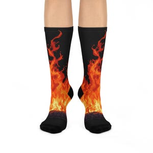 May include: Black socks with a vibrant orange and yellow flame design. The socks feature a pixelated fire pattern that extends from the foot to the calf. The heel and toe are black.