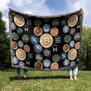 May include: A black woven throw blanket with a repeating pattern of cryptocurrency logos and internet meme characters. The logos include Bitcoin, Ethereum, Dogecoin, and Shiba Inu. The meme characters include Pepe the Frog and Doge.