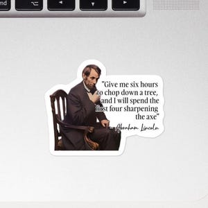 May include: A white sticker featuring a portrait of Abraham Lincoln seated in a chair. The sticker includes a quote attributed to Lincoln: "Give me six hours to chop down a tree, and I will spend the first four sharpening the axe."