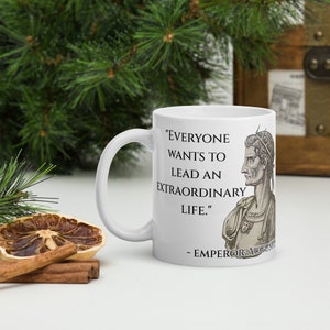 May include: White ceramic mug with a black quote that reads "Everyone wants to lead an extraordinary life." - Emperor Augustus. The quote is printed on the right side of the mug. A black and white illustration of Emperor Augustus is printed on the right side of the mug.