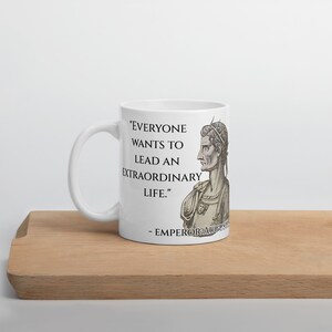 May include: White ceramic mug with a black and white image of Roman Emperor Augustus. The mug features a quote from Augustus: "Everyone wants to lead an extraordinary life."