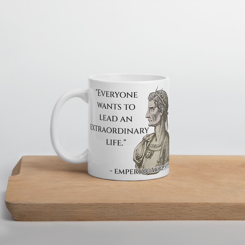May include: White ceramic mug with a black and white image of Roman Emperor Augustus. The mug features a quote from Augustus: "Everyone wants to lead an extraordinary life."