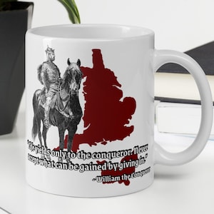 以下が含まれることがあります： 白磁のマグカップに、馬に乗った男性の白黒のイラストが描かれています。マグカップには、イギリスの赤い輪郭と、ウィリアム征服王の言葉「人生は征服者だけに屈する。決して屈することによって得られるものを受け入れるな。」が書かれています。