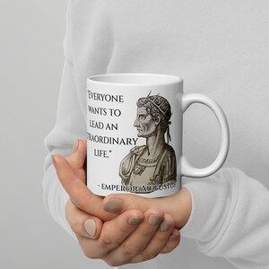 May include: White ceramic mug with a black and white image of Roman Emperor Augustus. The mug features a quote from Augustus: "Everyone wants to lead an extraordinary life."