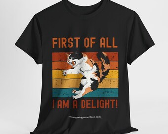 May include: Black t-shirt with a retro-style design featuring a cat with a surprised expression. The text reads "First of all I am a delight!" with a website address below.
