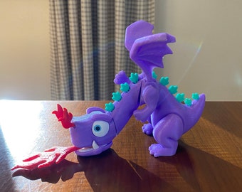 May include: A purple 3D printed dragon toy with a red flame coming out of its mouth. The dragon has green spikes on its back and wings.