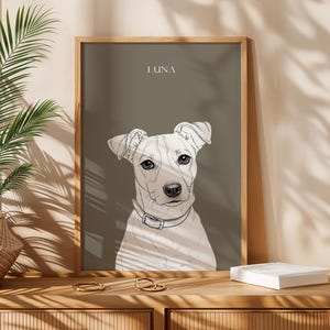 May include: A framed art print featuring a detailed sketch of a dog's face, set against a muted gray background. The dog is white with black accents, wearing a collar. The name "LUNA" is printed at the top. The frame is made of wood.