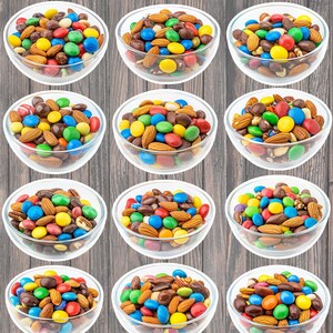 May include: Nine clear glass bowls filled with a mix of colorful candies and almonds. The candies are in various colors, including red, yellow, blue, green, and brown. The almonds are a light brown color. The bowls are arranged in a grid pattern against a wooden background.