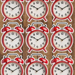 May include: Nine red alarm clocks with white faces and black hands are arranged on a wooden surface. Each clock has a classic design with a bell on top and a stand at the bottom. The clocks are evenly spaced.