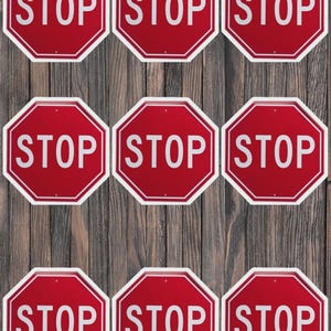 May include: Nine red octagonal stop signs with white text and borders are arranged on a wooden background. The word "STOP" is prominently displayed on each sign, creating a repetitive pattern.