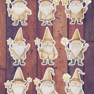 May include: Nine whimsical gnome stickers with long white beards, wearing pointed hats and coats in shades of tan and beige. Each gnome holds a star-shaped wand. The stickers are arranged on a dark wood-grain background.