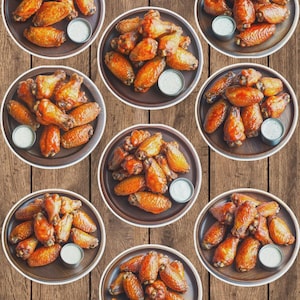 May include: A collage of eight plates of cooked chicken wings, each with a small dish of white dipping sauce. The wings are golden brown and arranged on round, wooden-toned plates, set against a wooden background.