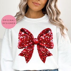May include: White sweatshirt with a large red sequin bow design.