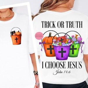May include: White t-shirt with a Halloween-themed design. The front features a small orange bucket with a cross, pumpkin, and candy. The back displays three buckets with candy and the text "TRICK OR TRUTH I CHOOSE JESUS John 14:6".