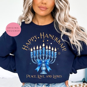 May include: A navy blue sweatshirt with a gold graphic of a menorah with lit candles and the text "Happy Hanukkah!" and "Peace, Love, and Latkes".