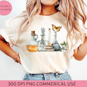 May include: Cream-colored t-shirt featuring a watercolor illustration of laboratory glassware, a butterfly, and botanical elements. The design includes a flask with a cork, a graduated cylinder, and a beaker. The text "ORIGINAL DESIGNER" is in a pink circle.