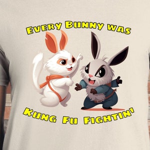May include: A white t-shirt with a cartoon image of two bunnies in a fighting stance. The text "Every bunny was kung fu fightin!" is printed in yellow on the shirt.