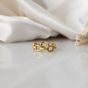 以下が含まれることがあります： シンプルなデザインのゴールドチェーンリング。リングは、複数のつながった楕円形のリンクでできています。