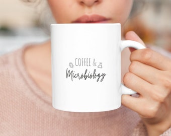 May include: White ceramic mug with black text that reads "Coffee & Microbiology" with a small leaf and beaker graphic.