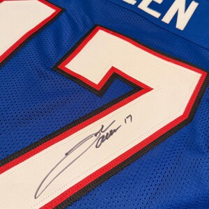 Puede incluir: Una camiseta de malla azul con el nombre "ALLEN" en letras blancas en la parte superior. El n&uacute;mero "17" se muestra prominentemente en blanco con ribetes rojos y negros. Se puede ver una firma en la camiseta.