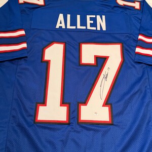 Puede incluir: Una camiseta de f&uacute;tbol azul con el nombre "ALLEN" en la espalda y el n&uacute;mero "17" en blanco con ribetes rojos y negros. La camiseta tiene rayas blancas y rojas en las mangas y una firma en el n&uacute;mero.