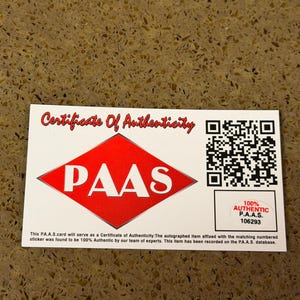 Puede incluir: Un certificado blanco con texto rojo que dice "Certificate Of Authenticity". El certificado tiene un diamante rojo con "PAAS" en blanco. Una pegatina dice "100% Authentic P.A.A.S. 106293".