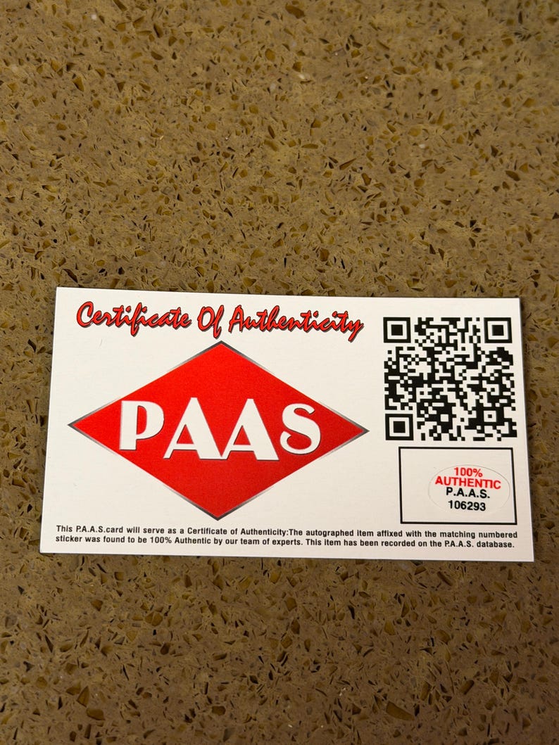 Puede incluir: Un certificado blanco con texto rojo que dice "Certificate Of Authenticity". El certificado tiene un diamante rojo con "PAAS" en blanco. Una pegatina dice "100% Authentic P.A.A.S. 106293".