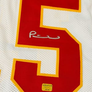 Puede incluir: Una camiseta deportiva de malla blanca con un n&uacute;mero cinco grande de color rojo y borde amarillo. El n&uacute;mero incluye una firma plateada en el centro y una pegatina de autenticaci&oacute;n dorada rectangular en la parte inferior con el texto GOLDENCERTS.COM.