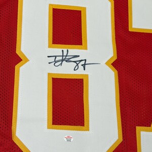 May include: Red jersey with the number 87 in white with gold trim. The number is signed in black ink. The jersey has an "AUTHENTIC" sticker.
