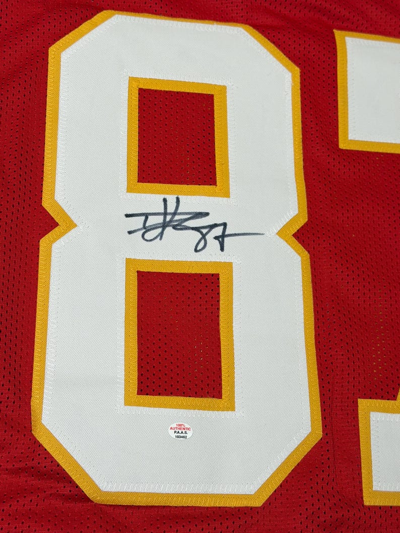 May include: Red jersey with the number 87 in white with gold trim. The number is signed in black ink. The jersey has an "AUTHENTIC" sticker.