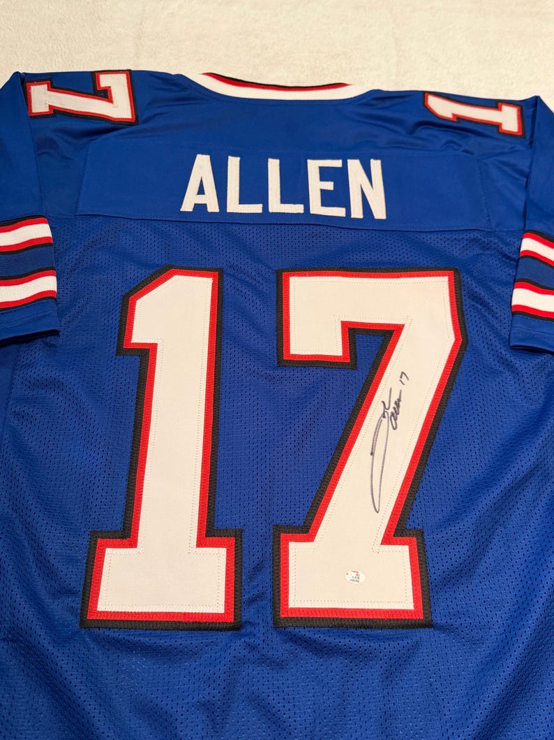 Puede incluir: Una camiseta de malla azul con el nombre "ALLEN" en la espalda y el n&uacute;mero "17" en blanco con ribete rojo. La camiseta tiene una firma en el n&uacute;mero 17. La camiseta tiene rayas blancas y rojas en las mangas.