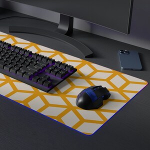 May include: A yellow and white geometric patterned mousepad with a black keyboard and a black mouse on a black desk with a computer monitor.