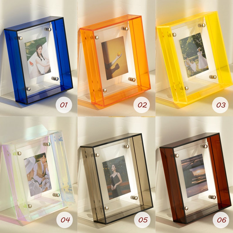 Op de afbeelding: Een verzameling van zes acryl fotolijsten in verschillende kleuren: blauw, oranje, geel, iriserend, grijs en bruin. Elke lijst bevat een foto en wordt bij elkaar gehouden met zilverkleurige hardware. De lijsten zijn ontworpen om rechtop te staan.