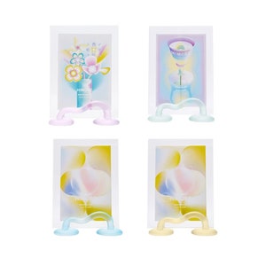 May include: Four white picture frames with colorful abstract designs and the word "HIMORE" printed on each. Each frame is held up by a clear, wavy, glass stand with two round bases.