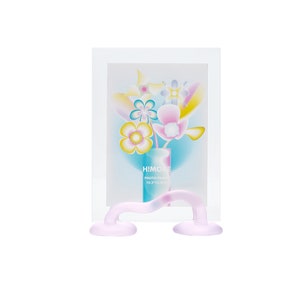 May include: A pink glass photo frame with a clear glass front and a wavy stand. The frame has a colorful floral design inside and the text "HI!MOLE PHOTO FRAME 10.2"*12.7"*2.5CM" printed on the bottom.