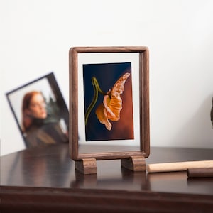 May include: A wooden picture frame with a stand, displaying a photograph of an orange poppy flower against a dark blue and orange background.