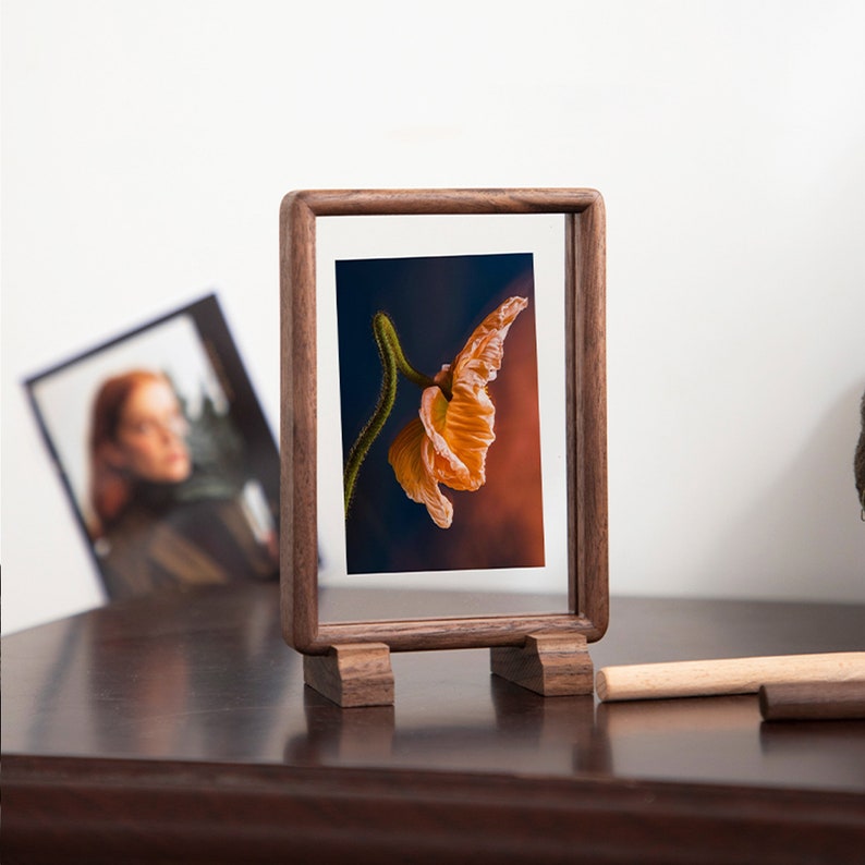 May include: A wooden picture frame with a stand, displaying a photograph of an orange poppy flower against a dark blue and orange background.